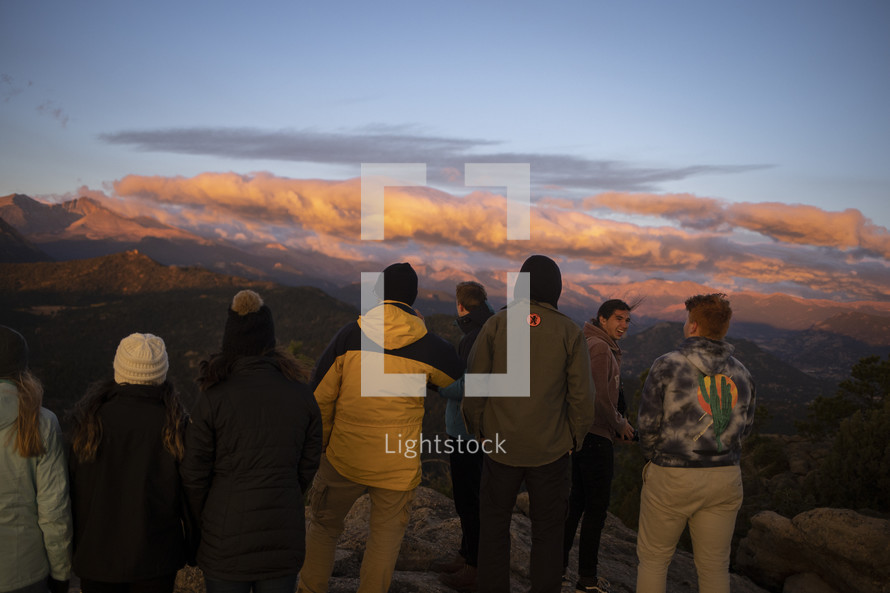group of friends watching the sunrise on a mountaintop 
