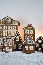 home made gingerbread village in front of white background on white snowlike velvet as advent decoration