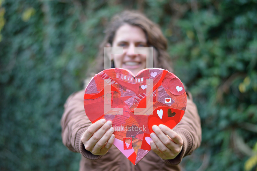 woman holding up a cutout paper heart