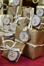 advent calendar with twenty four golden presents on red wood with the numbers burned into round wood pieces and the numbers 20, 3 and 2 up close