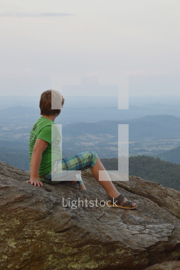 a boy enjoying a view from a mountaintop 