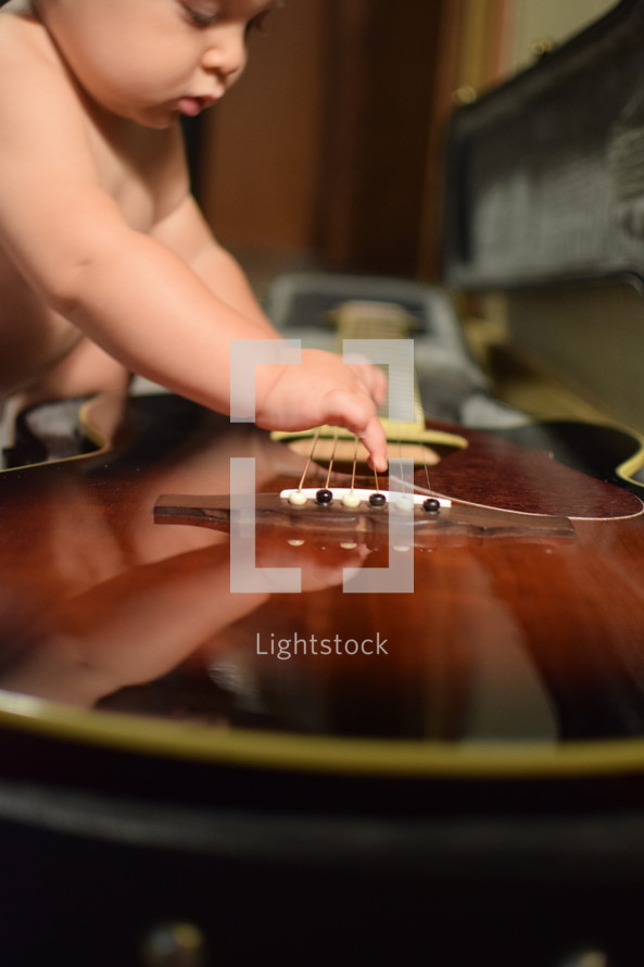 an infant strumming a guitar 