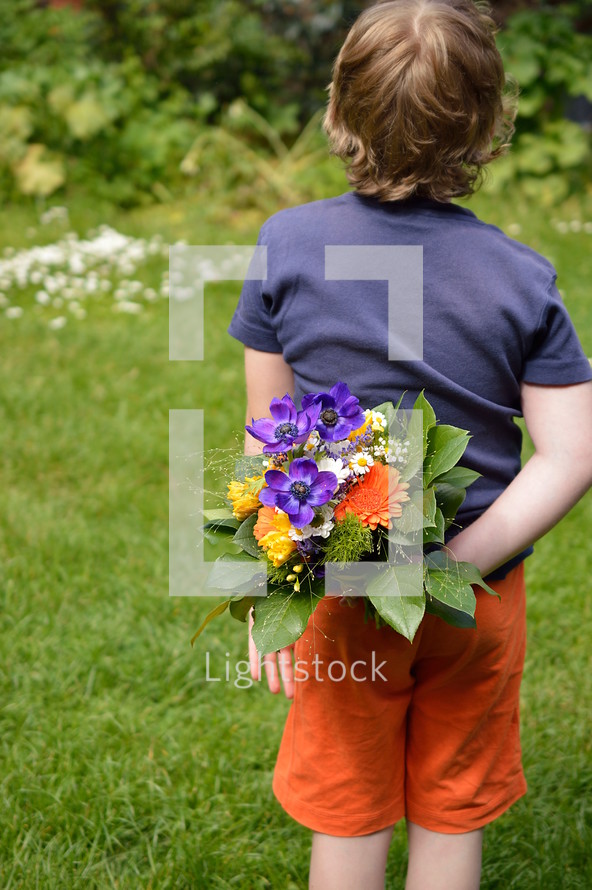 a boy child holding a bouquet of flowers for mom 