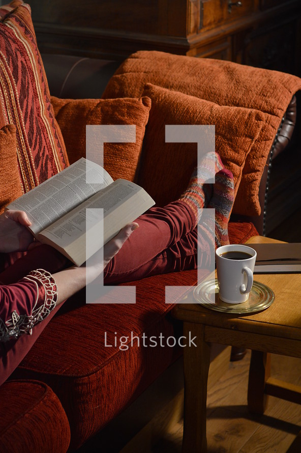 a woman reading a Bible on a couch