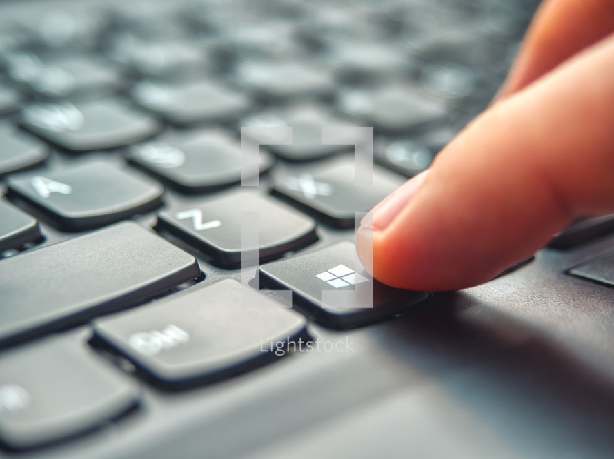 Laptop user pressing Windows Key on Microsoft Windows keyboard