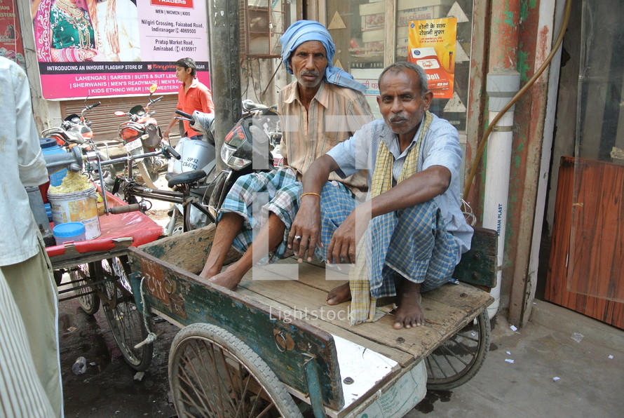 two men sitting in a pedicab wagon