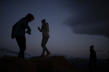 silhouettes of people on a mountaintop in darkness 