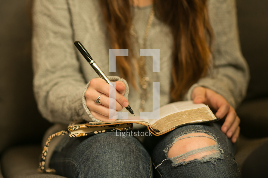A teen girl reading and high lightening a Bible 
