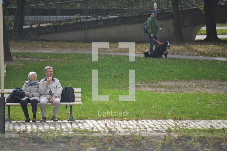 elderly couple sitting on a bench in a park