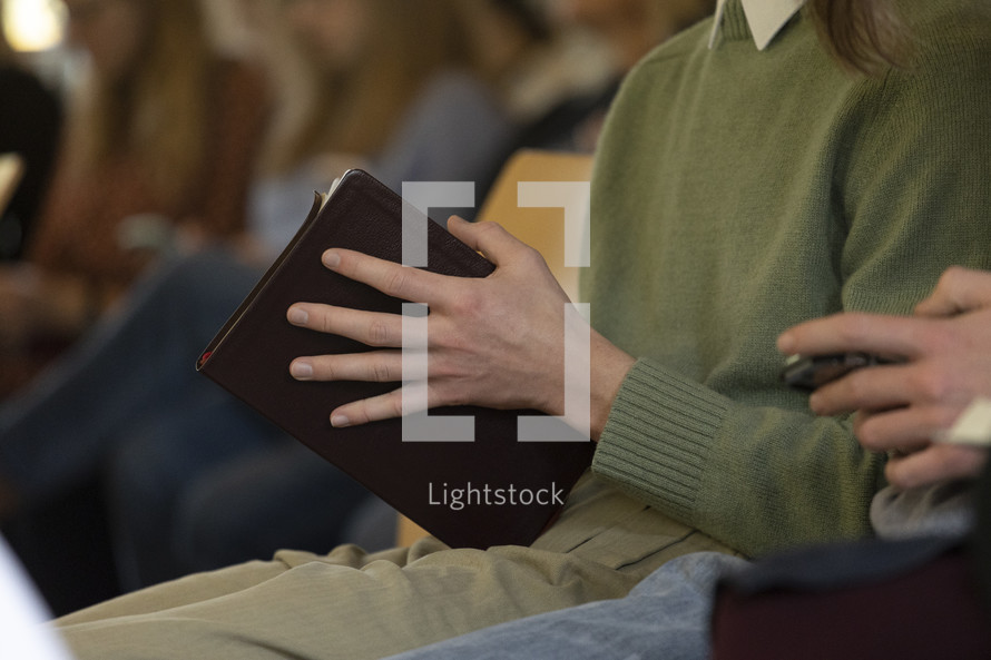 Close up of people holding Bibles on a row
