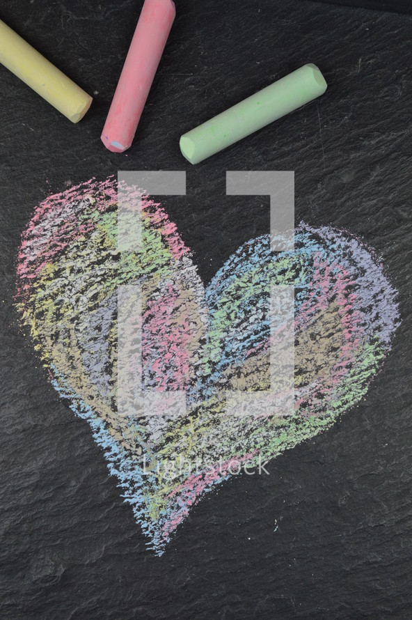 heart shape in sidewalk chalk on slate with chalk sticks