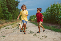 Happy Kids Running Together With Golden Retriever Puppy On Green Nature Background. Smiling Brothers.