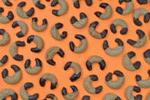 pattern out of home made nougat crescents cookies with chocolate at the edges on orange background