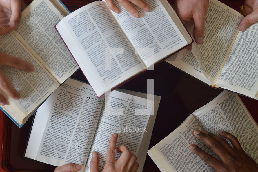 Hands holding bibles in different languages open at 2 kings 15. 
