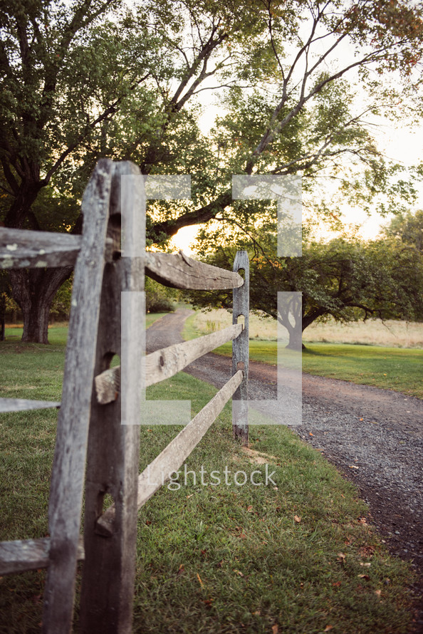 rustic wood fence along a gravel road 