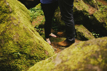 feet of a couple standing on moss covered rocks
