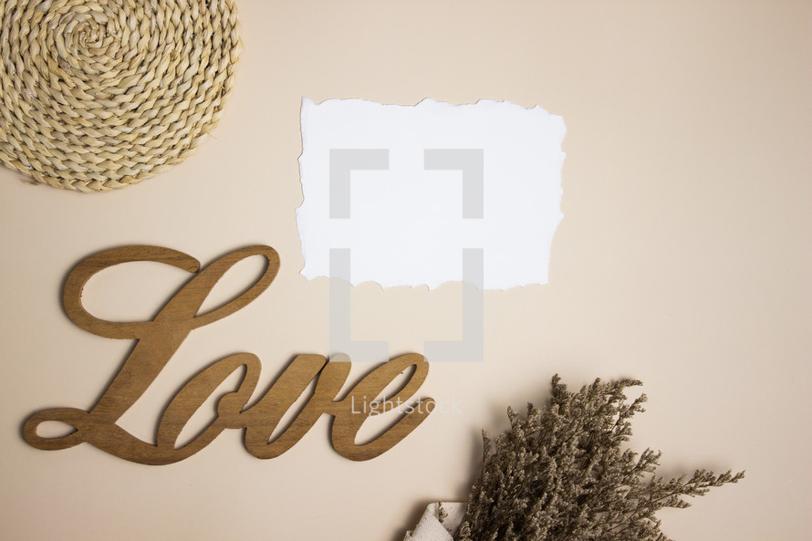 Blank white note with the word love and bouquet on tan background
