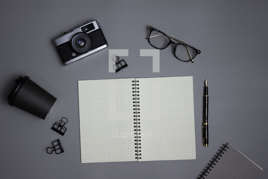Business notebooks with glasses, camera, cup, and office supplies