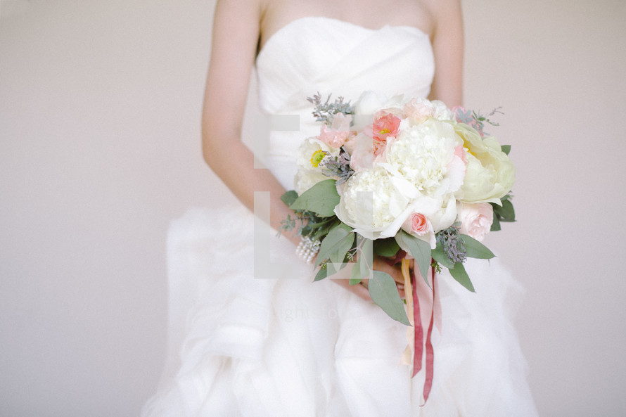 torso of a bride holding her bouquet 