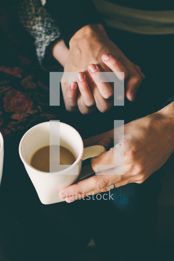 couple holding hands and coffee mug