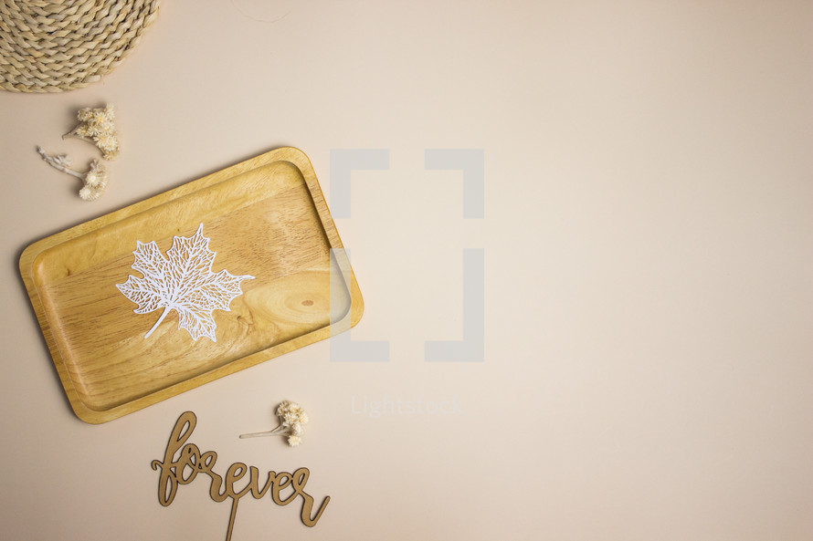 White leaf on wooden plate and tan background