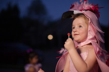 a toddler in a flamingo Halloween costume holding a lollipop 