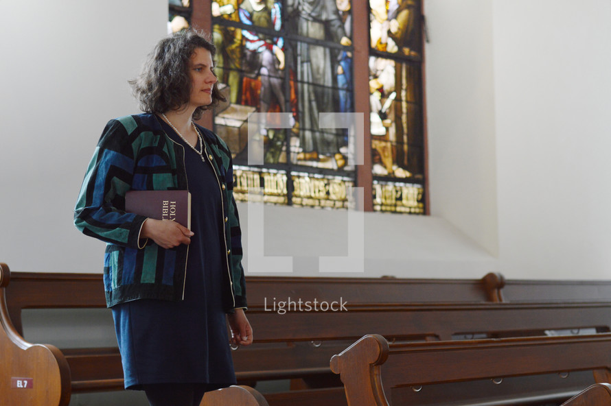 a woman walking into a church carrying a Bible 