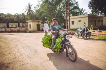 man riding a motorcycle covered in bananas 