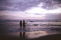 Silhouette of a boy and girl walking along the beach.