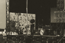 man on stage at an outdoor worship service 