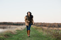 young woman walking in a coat and boots outdoors 