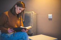 a woman sitting on a bed reading a Bible 