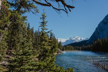 river, snow capped mountains and evergreen forest 