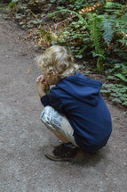 a boy squatting on a path praying 