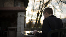 man sitting outdoors reading a Bible 