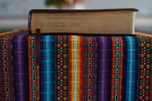 a Bible on a colorful blanket 