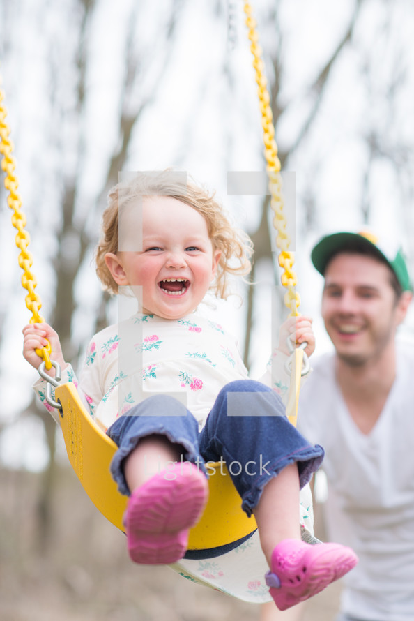 happy toddler girl on a swing 