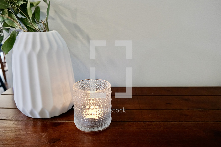 a vase and candle on a wood table 