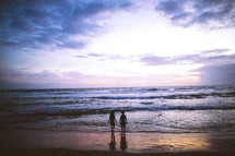The silhouette of children on a beach at dusk. 