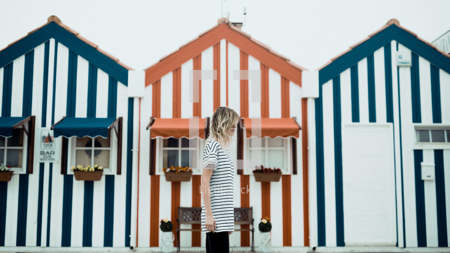 a woman walking in front of striped houses 