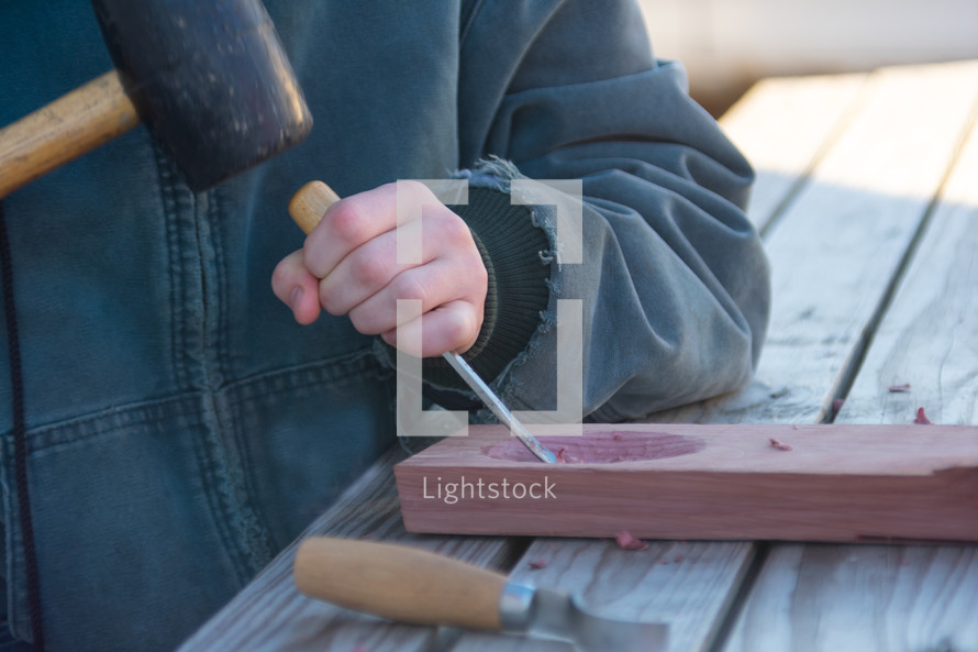 a boy chiseling wood 