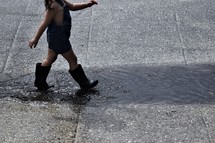 a toddler girl walking through puddles in rain boots 