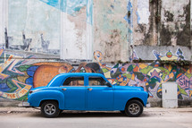 vintage car and graffiti covered wall in Havana, Cuba 