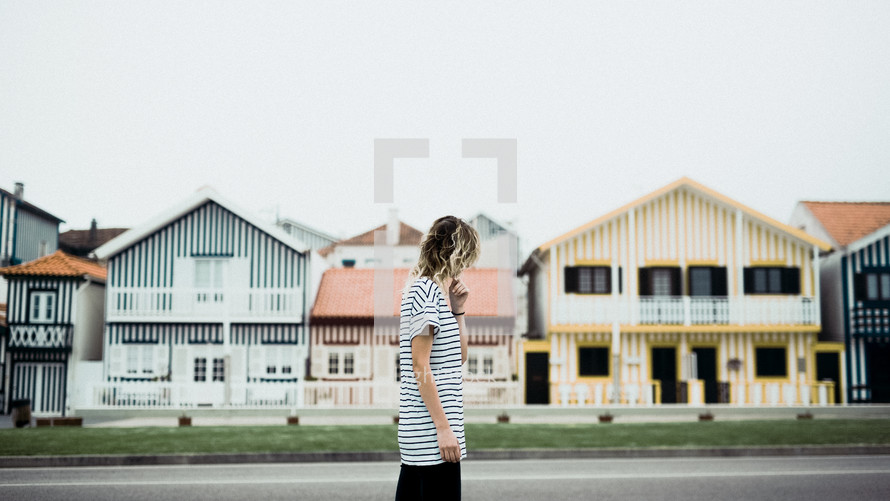a woman walking in front of striped houses 