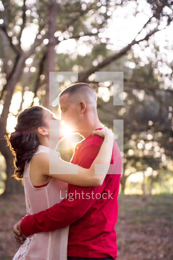 Couple embracing at sunrise in the woods.