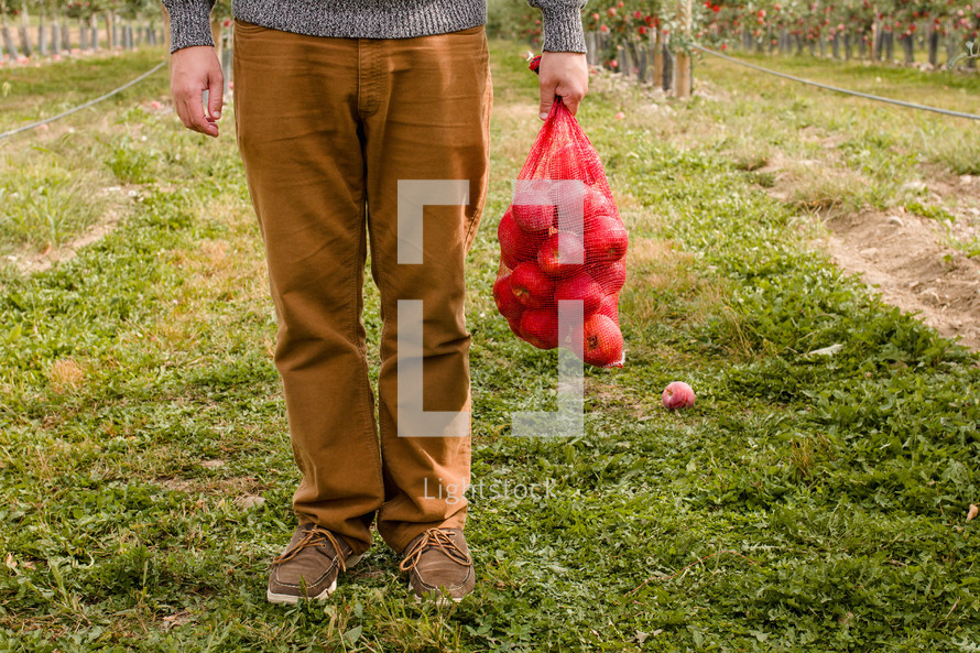 man holding a sack of apples 