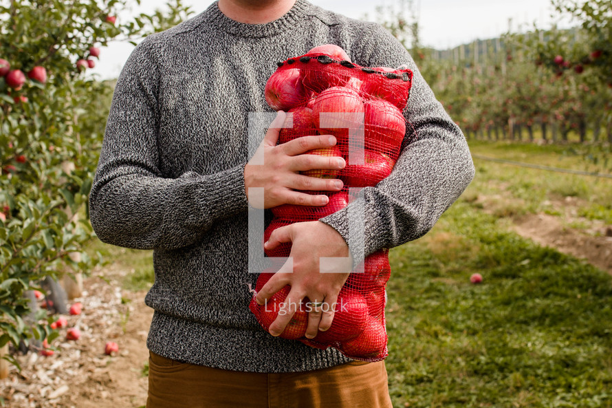 man standing with a sack of apples 