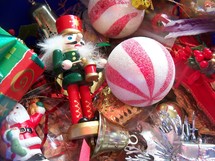 A box of Christmas Ornaments sit patiently waiting to decorate a home for the holidays including a Nutcracker, Santa Claus, Silver Bell, green and red tree ornaments ready to adorn the family tree to usher in the season. 