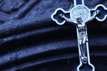 silver crucifix necklace on blue cloth