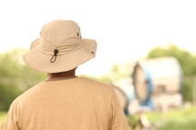 a man in a safari hat with his back to the camera 